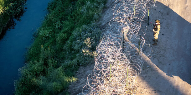 A US troop stands at a barbed wire fence on the US-Mexico border