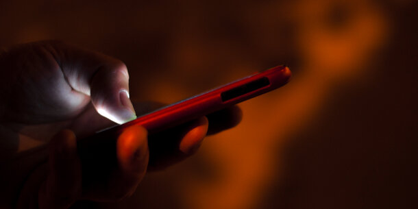 person holding cell phone on dark background