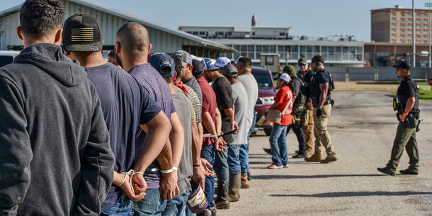 A group of men being apprehended by immigration agents
