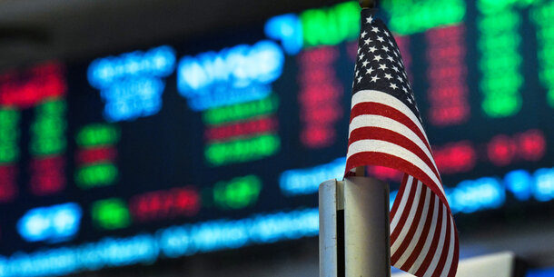U.S. flag in front of a display of stock prices