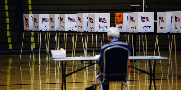 Worker in foreground, row of empty voting booths in background