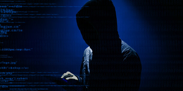 Hooded figure surrounded by lines of computer code