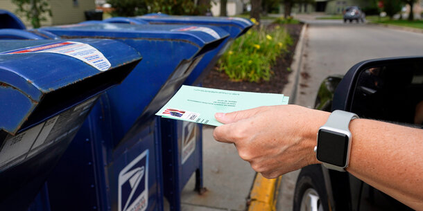 Mail ballot being dropped in mail slot