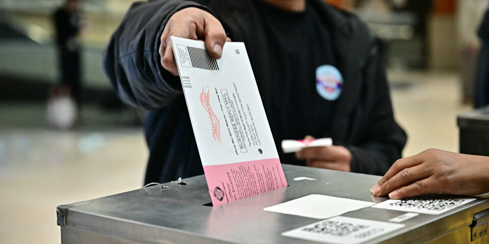 A mail ballot is dropped into a dropbox. 