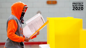 A voter in a face covering entering a voting booth.