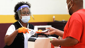 Poll worker with PPE and voter with mask
