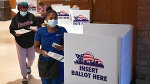 woman placing ballot in voting box.