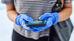 person wearing surgical gloves holding a smart phone