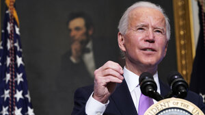 President Joe Biden talking to the press in front of a portrait of Abraham Lincoln.