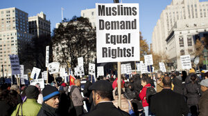 a protestor holds a sign that reads "Muslims demand equal rights!"
