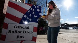 A person standing in front of a ballot drop box.