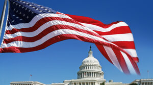 The United States flag flying in front of the Capitol building.