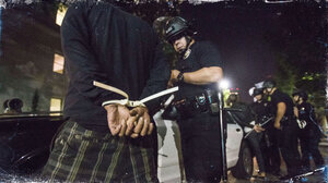 Person restrained by police officers with zip ties