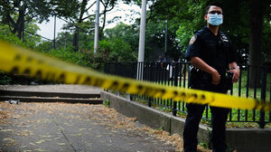 Police officer stands behind yellow tape