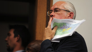 Legislator looks pensive while holding Colorado communities map