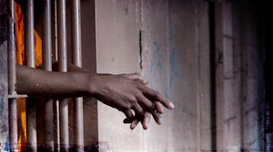 Hands stick out from behind prison bars