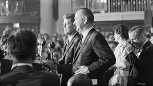 John F. Kennedy and Lyndon Johnson stand together at a podium.
