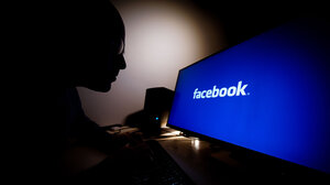 person sitting at a computer with facebook logo on the screen