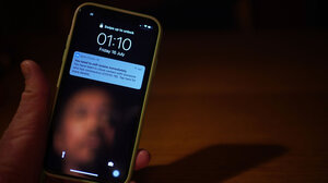 A man's face is reflected in a smartphone screen which shows a Covid-19 exposure notification