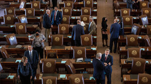 State legislators intermingle around a legislative chamber