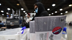 An election worker sorts mailed ballots, with a close up shot of one sealed with an "I Voted" sticker