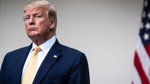 Former President Trump looks at the camera, with an American flag in the background