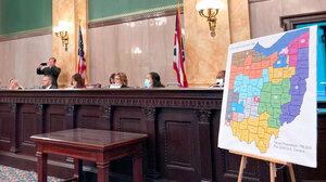A panel of politicians sits by a large print of a proposed Ohio redistricting map on an easel