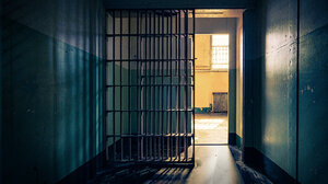 View of the inside of a jail cell, partially left open with sunshine pouring in