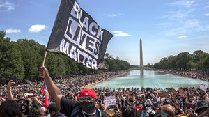 Black Lives Matter protestor holds up a flag at a rally at the Washington Monument