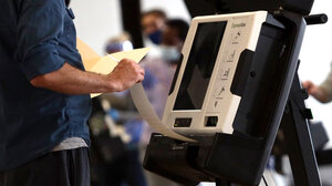  A voter pulls a ballot print-out from a voting machine