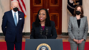Judge Ketanji Brown Jackson speaks at the presidential podium flanked by President Biden and Vice President Harris