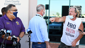 A man yells at an election official in front of press outside the Clark County Election Center