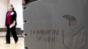 Woman walks past a Dominion Voting machine