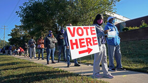 VOTE HERE sign next to long line of people waiting to vote