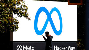A man using his phone walks by Meta headquarters