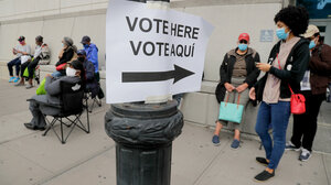 A bilingual English-Spanish "vote here" sign surrounded by voters in line