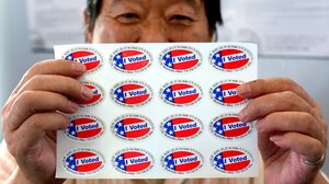 Asian American man holding "I Voted" stickers