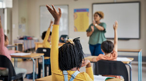 little girl of color raising her hand in a classroom