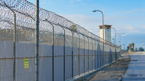 barbed wire fence with guard tower in background