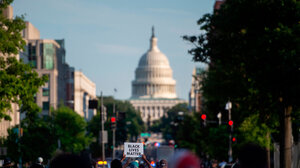 Capitol building in background and "Black Lives Matter" sign held up in the foreground