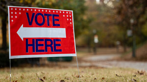 Red sign that has vote here text with white arrow