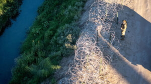 A US troop stands at a barbed wire fence on the US-Mexico border