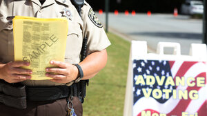 law enforcement officer holding ballot outside polling place