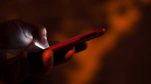 person holding cell phone on dark background