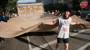 Photo of man carrying giant copy of the U.S. Constitution in demonstration. 