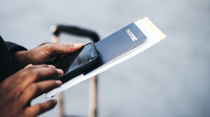 Man at airport holding passport and phone