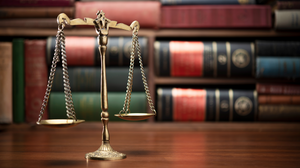 The scales of justice sit in front of legal books. 