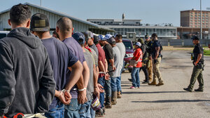 A group of men being apprehended by immigration agents