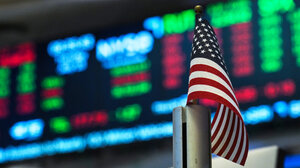 U.S. flag in front of a display of stock prices