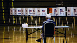 Worker in foreground, row of empty voting booths in background